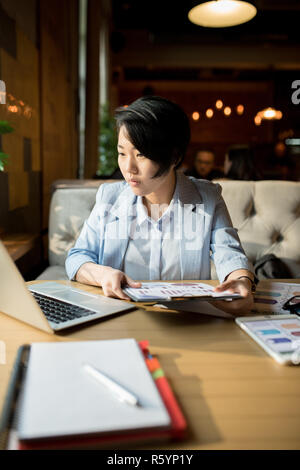Concentrato consigliere asiatici analizzando il grafico in cafe Foto Stock