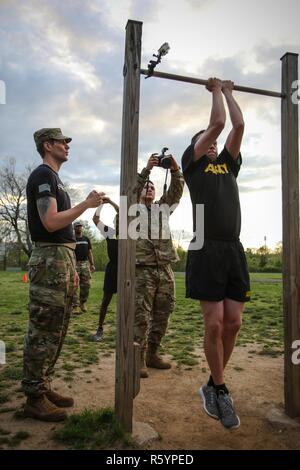 Stati Uniti Il personale dell'esercito Sgt. Brian Kohl, assegnato alla 55th Signal Company (lotta contro la telecamera), gradi Spc. William Lockwood, assegnato alla 55Signal Company (lotta contro la telecamera), come egli esegue 55 di pull-up che è parte dell'Hilda la sfida che il design è per testare la resistenza fisica durante il 2017 quinto annuale SPC Hilda I. Clayton meglio combattere la telecamera (COMCAM) Concorrenza a Fort George G. Meade, Md., 17 aprile 2017. Lockwood è competere nel 2017 quinto annuale migliore concorrenza COMCAM dove squadre di due competere per tutta la durata di un evento di giro che le prove del loro stato fisico e mentale e di capacità tecniche. Il Foto Stock