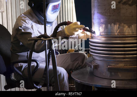 Saldatore con maschera protettiva in metallo di saldatura e le scintille Foto Stock