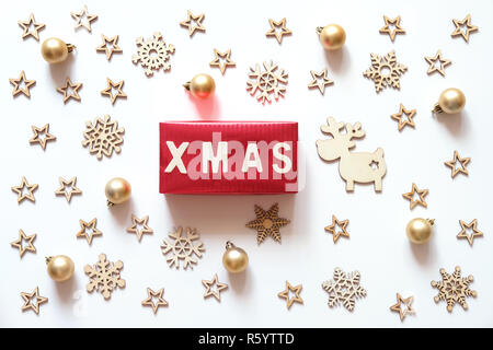 Vacanze di Natale sfondo. Xmas parola fatta di lettere in legno sulla confezione regalo rossa con decorazioni natalizie su sfondo bianco. Foto Stock