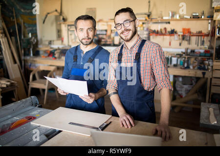 Due lavoratori che pongono in officina per la lavorazione del legno Foto Stock