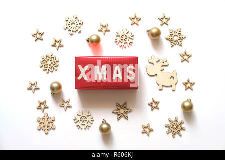 Vacanze di Natale sfondo. Xmas parola fatta di lettere in legno sulla confezione regalo rossa con decorazioni natalizie su sfondo bianco. Foto Stock