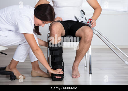 Medico donna mettendo il rinforzo a piedi sulla persona della gamba Foto Stock