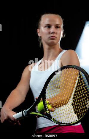 Ritratto di donna bella giocando a tennis indoor. Isolato su nero. Foto Stock