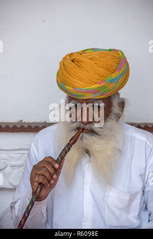 Uomo indiano con Turban giallognolo che fuma l'hookah, Forte Mehrangarh, Jodhpur, Rajasthan, India Foto Stock
