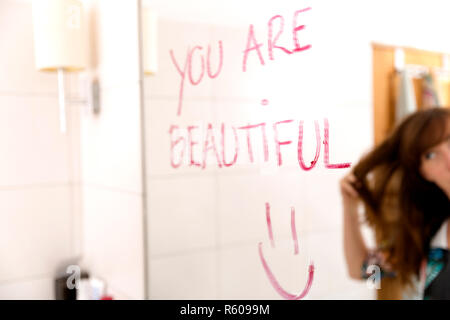 Incoraggiare le donne se stessa mediante la scrittura di parole che sono belle a specchio con il rossetto Foto Stock