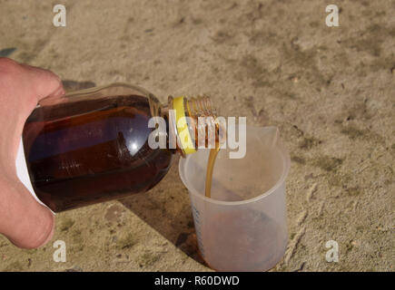 Versando il glifosato spessa soluzione in un beaker Foto Stock