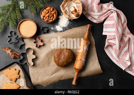 Gingerbread cookie cottura. Vacanze di Natale cottura sul calcestruzzo nero lo sfondo. Vista superiore Foto Stock