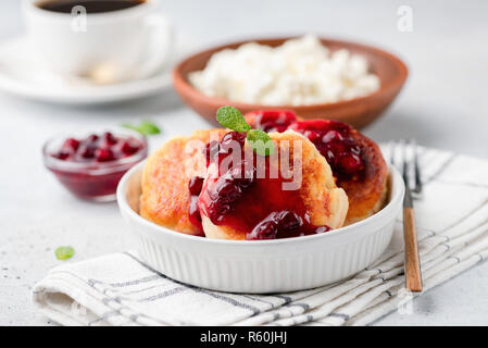 Syrniki o ricotta frittelle con marmellata di mirtilli. Russo, Ucraino cucina. Formaggio fritto polpette con salsa dolce Foto Stock