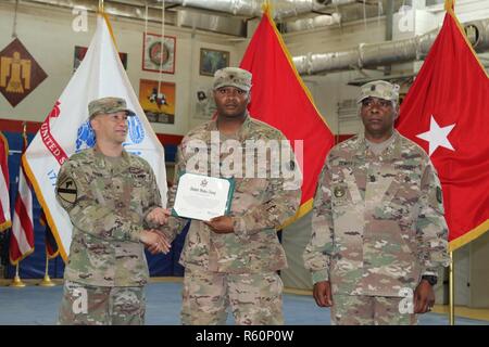 Stati Uniti Esercito Brig. Gen. Stephen Hager (sinistra), commander, 335a comando di segnalazione, si congratula con l'esercito Spc. Deonte Monteria (centro), automatizzato Specialista di logistica, 978th Quartermaster Company, a continuare il suo impegno per gli Stati Uniti Esercito si riserva il 22 aprile a Camp Arifjan in Kuwait. La riserva di esercito di cella di impegno ha ospitato questo evento annuale come parte di una giornata celebrativa orientata verso onorare gli uomini e le donne che servono negli Stati Uniti Riserve dell'esercito. Foto Stock