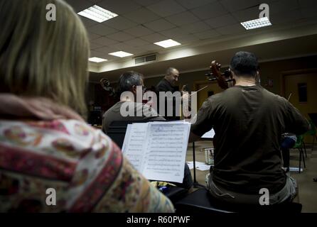 Il cap. Justin Lewis, U.S. Forze Aeree del comando centrale responsabile della banda in carica, effettua una prova con la comunità di Doha Orchestra in preparazione per un concerto insieme con la banda AFCENT Aprile 26, 2017. Il concerto si è tenuto il 29 aprile 2017 presso la scuola americana di Doha. Gli Stati Uniti Le forze di aria di comando centrale di banda è il primo permanentemente assegnato Air Force Band alla centrale di comando Area di responsabilità. In base Al Udeid Air Base, Qatar, la banda è compresa di distribuito aviatori da active duty, Riserva e Air National Guard bande. Foto Stock