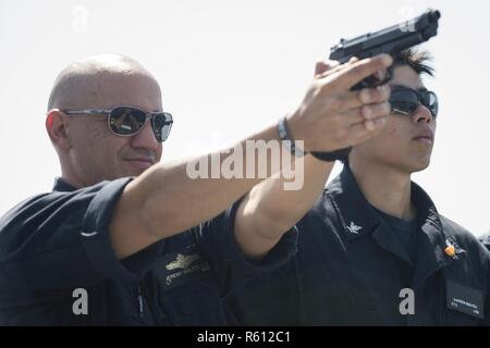 Mare Mediterraneo (5 maggio 2017) Lt. Jeremy Maldonado, sinistra, dimostra arma familiarizzazione prima di un 9 mm Pistol Qualificazione a bordo del Arleigh Burke-class guidato-missile destroyer USS Ross (DDG 71) 5 maggio 2017. Ross, distribuita a Rota, Spagna, sta conducendo operazioni navali negli Stati Uniti Sesta flotta area di operazioni a sostegno degli Stati Uniti per gli interessi di sicurezza nazionali in Europa e in Africa. Foto Stock