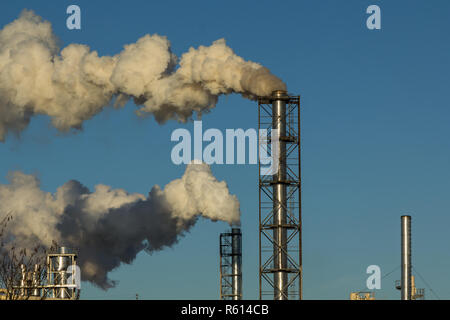Comignoli fumanti legno impianto di lavorazione su uno sfondo di cielo blu Foto Stock