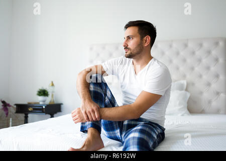 Ritratto di uomo infelice seduta sul letto Foto Stock