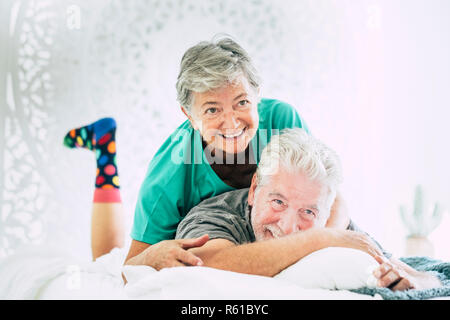 Adulto felice cople giocare e divertirsi sul letto di casa al mattino - Nizza gioioso stile di vita per i pensionati - immagine luminosa con calze colorate un Foto Stock
