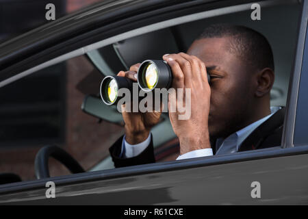 L'uomo africano guardando attraverso il binocolo Foto Stock