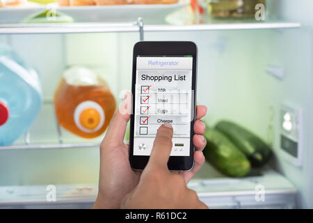 Persona mani marcatura Shopping List sul telefono cellulare Foto Stock