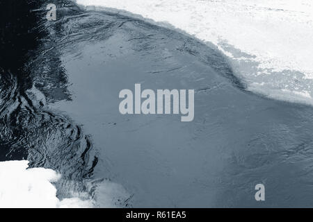 Il Ghiaccio coperto di neve ai lati del fiume congelato nella stagione invernale, lo sfondo naturale texture foto Foto Stock