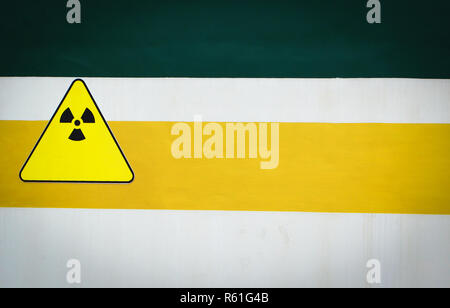Segnale di avvertimento attenzione di radiazione sulla parete verde giallo e sfondo bianco Foto Stock