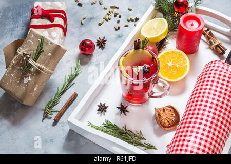 Vin brulè, una bottiglia di vino rosso, Abete rami, cannella, arancio e limone sul vassoio bianco su sfondo di calcestruzzo. Bevande d'inverno. Vigilia di Natale Foto Stock