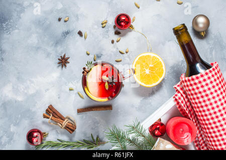 Vin brulè, una bottiglia di vino rosso, Abete rami, cannella, limone e arancio su sfondo di calcestruzzo. Bevande d'inverno. Vigilia di Natale Foto Stock