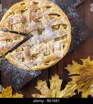 Cotto intero round la torta di mele su un vecchio rettangolare scheda marrone Foto Stock