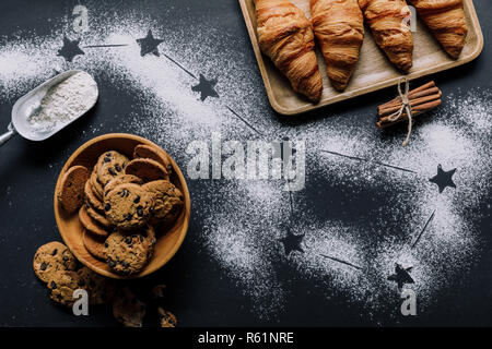 Lay piatto con cornetti e biscotti sul tavolo coperti da farina con stelle come big dipper constellation Foto Stock
