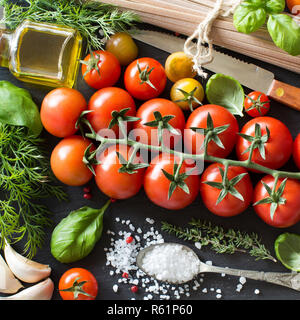 La cucina italiana ingridients : pomodori ciliegia, erbe aromatiche, pasta e olio di oliva Foto Stock