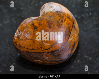 Burattati occhio di tigre pietra su sfondo scuro Foto Stock