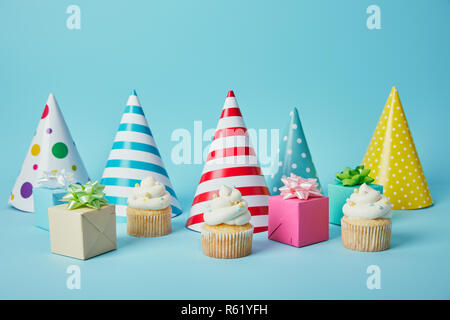 Festa colorati cappelli, doni e Deliziose tortine su sfondo blu Foto Stock