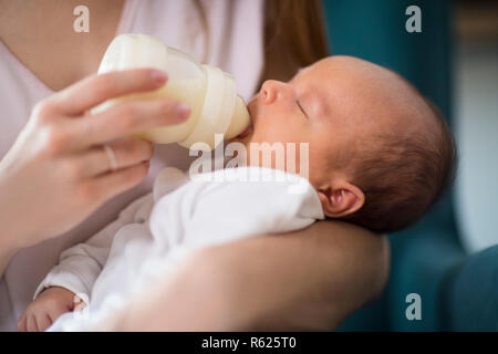 Close Up di Madre amorevole alimentazione neonato Figlio con bottiglia in casa Foto Stock