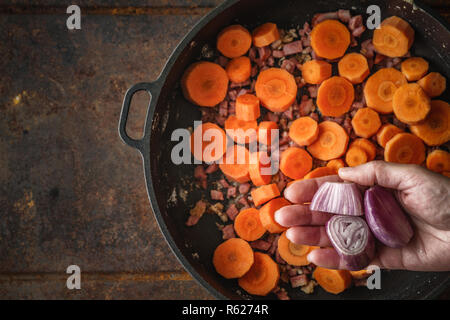 Aggiunta di scalogno in padella con la pancetta e carote vista superiore Foto Stock