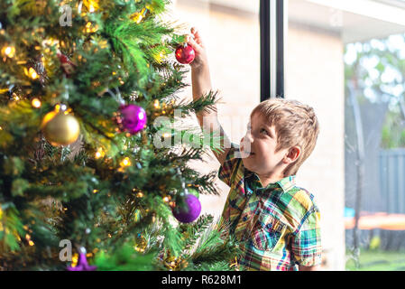 Carino sorridente bambino decorare un albero di Natale in Sud Australia Foto Stock