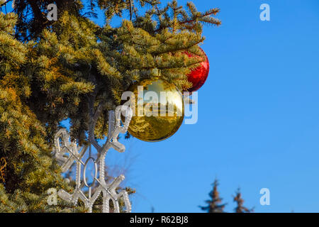 Decorazioni Anno nuovo albero. Tinsel e giocattoli, le sfere e le altre decorazioni di Natale sulla struttura ad albero di Natale in piedi in aria aperta. Foto Stock