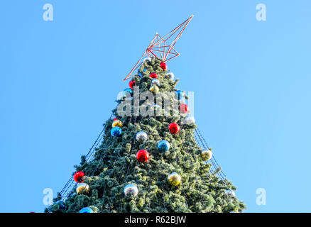 Decorazioni Anno nuovo albero. Tinsel e giocattoli, le sfere e le altre decorazioni di Natale sulla struttura ad albero di Natale in piedi in aria aperta. Foto Stock