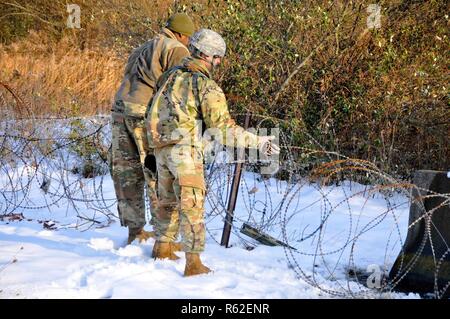 Stati Uniti Pfc dell'esercito. Isaia Bennett, sinistro e il cap. Sean Malloy, con sede e Sede Società, 28th Expeditionary combattere la Brigata Aerea, luoghi di filo di concertina durante una formazione sul campo esercizio su una coperta di neve campo a Fort Indiantown Gap, Pennsylvania Novembre 16, 2018. Foto Stock