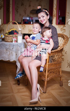 Ritratto di madre e due figli all'interno della cucina, girato in stile retrò. Studio shot, arredamento. Foto Stock