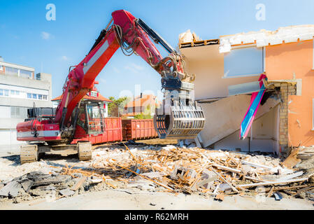 Un escavatore la demolizione di case per la ricostruzione. Foto Stock