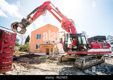 Un escavatore la demolizione di case per la ricostruzione. Foto Stock