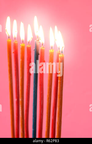 Hanukkah candele accese sullo sfondo rosa in verticale Foto Stock