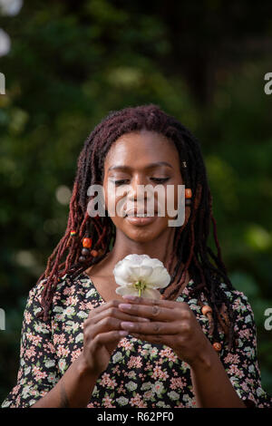 Primo piano di una donna che guarda una rosa Foto Stock