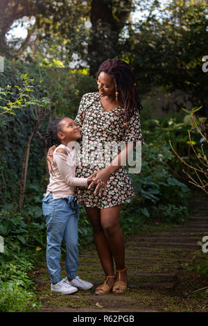 Madre e figlia guardando ogni altra amorevolmente su un percorso da giardino Foto Stock