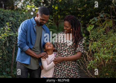 Una madre, padre e figlia di guardare tutti gli altri con amore in un parco Foto Stock