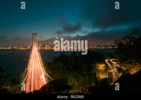 Bay Bridge di San Francisco Bay Area di notte con una lunga esposizione mostra traffico sentieri di notte e lo skyline Foto Stock