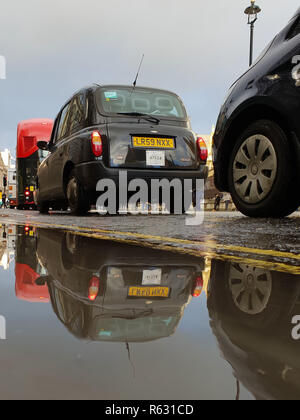 Westminster. Londra, Regno Unito. 3 dicembre, 2018. Una riflessione di Londra taxi nero nella pozza d'acqua di fronte Palazzo di Westminster. Pioggia pesante a Londra ha causato la raccolta di acqua. Credito: Dinendra Haria/Alamy Live News Foto Stock