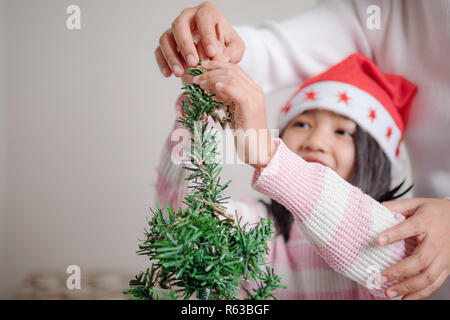 Asian bambina con la madre la decorazione albero di natale per party con la felicità Foto Stock