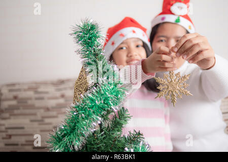 Asian bambina con la madre la decorazione albero di natale per party con la felicità, selezionare focus leggera profondità di campo Foto Stock