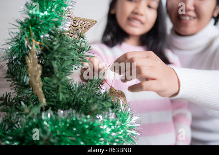 Asian bambina con la madre la decorazione albero di natale per party con la felicità, selezionare focus leggera profondità di campo Foto Stock