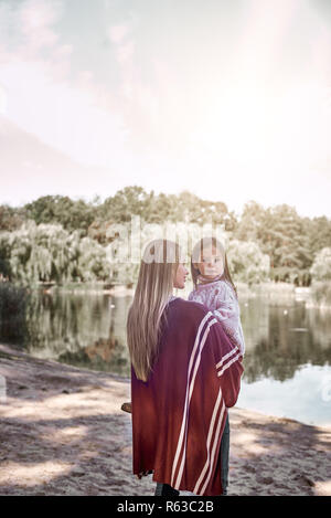 Felice, ragazza huggs sua madre bella vicino al lago Foto Stock