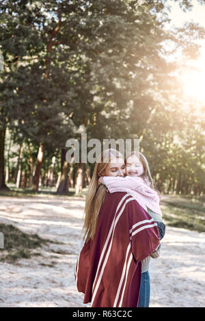 Felice, ragazza huggs sua madre bella vicino al lago Foto Stock